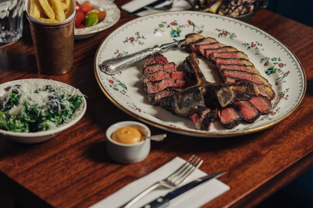 Plate of Philip Warren steak on table with chips and sides